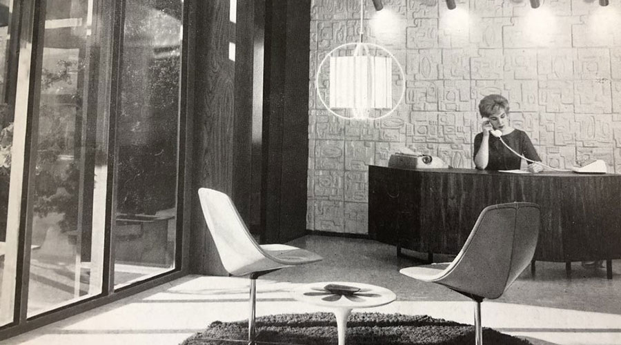 black and white photo of lobby with woman behind desk