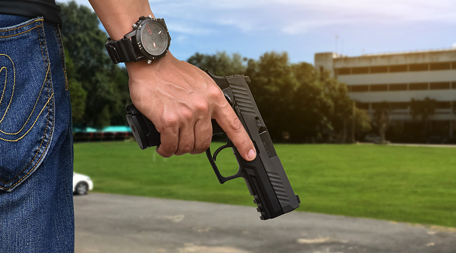 person with gun in front of building