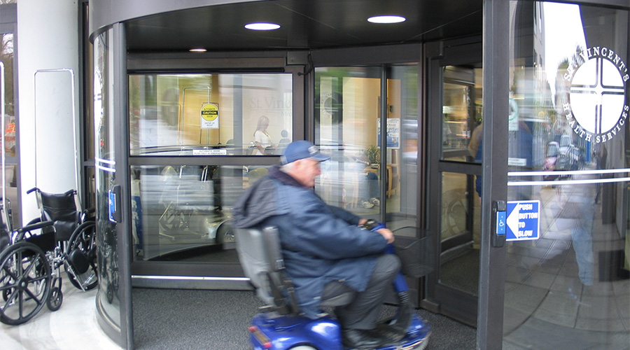 Someone with a wheelchair using an automatic revolving door